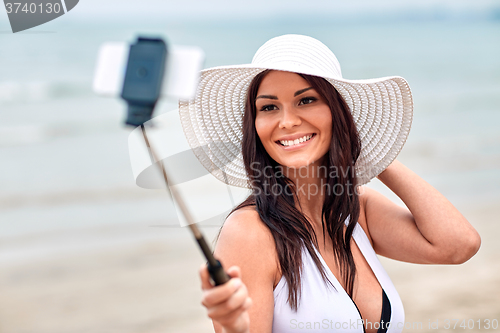 Image of smiling young woman taking selfie with smartphone