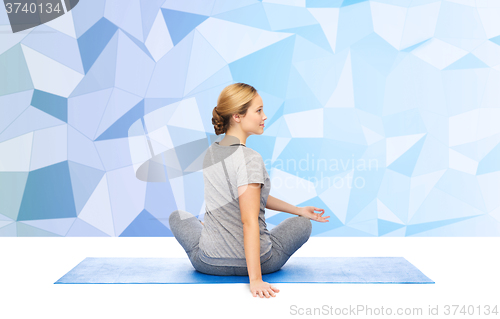 Image of woman making yoga in twist pose on mat