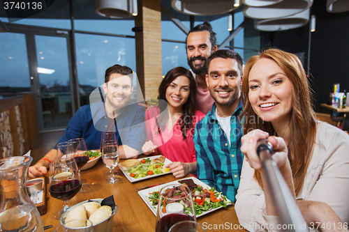 Image of friends picturing by selfie stick at restaurant