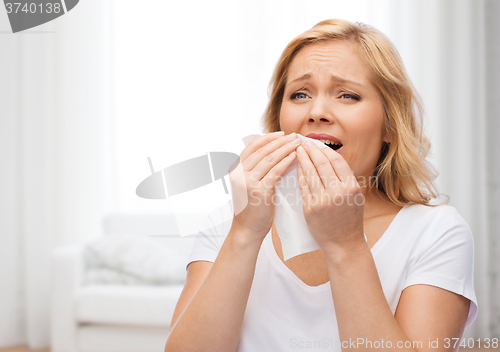 Image of unhappy woman with paper napkin sneezing