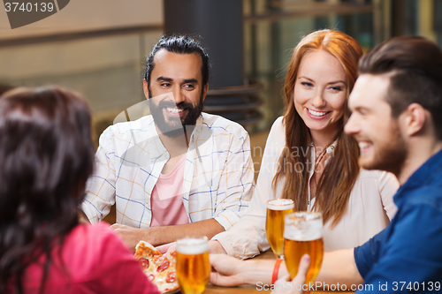 Image of friends eating pizza with beer at restaurant