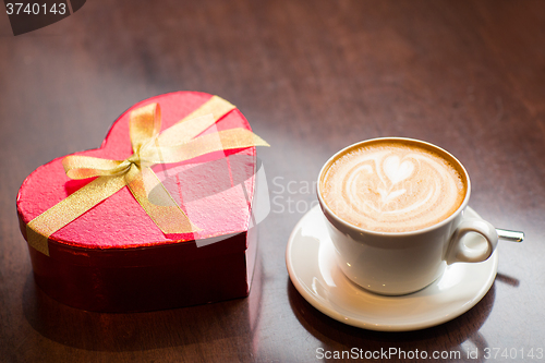 Image of close up of gift box and coffee cup on table