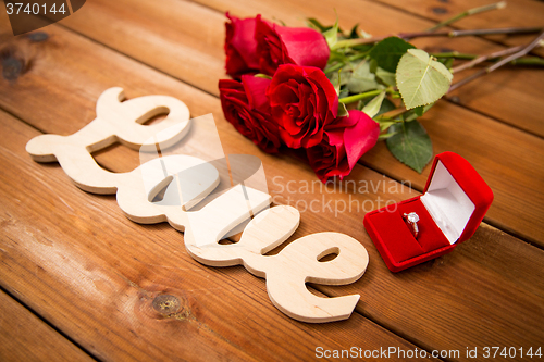 Image of close up of diamond ring, red roses and word love