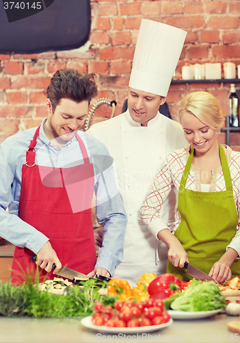 Image of happy couple and male chef cook cooking in kitchen