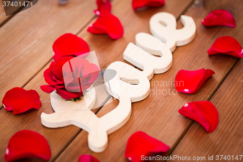 Image of close up of word love cutout with red rose on wood
