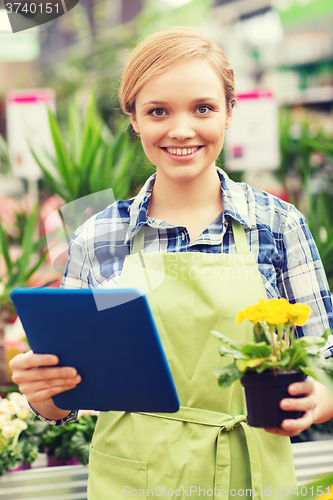 Image of happy woman with tablet pc in greenhouse