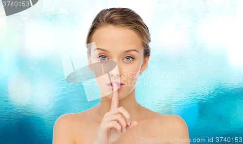 Image of beautiful young woman holding finger on lips