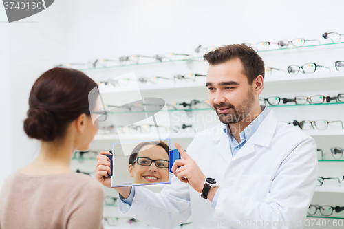 Image of woman in glasses looking to mirror at optics store