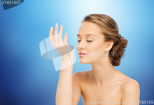 Image of woman smelling perfume from wrist of her hand