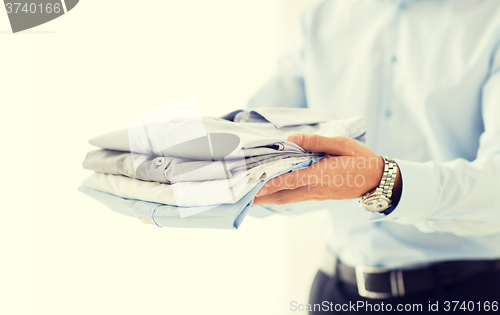 Image of close up of businessman holding folded shirts