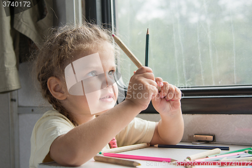 Image of Girl looks funny on pencils at the table in the second-class train carriage