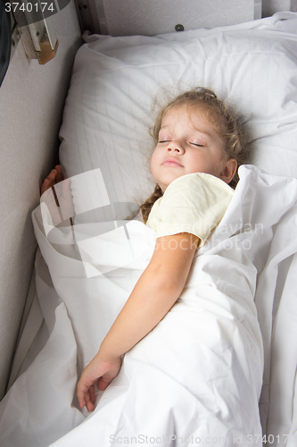 Image of Four-year girl sleeping on the bottom shelf in a train