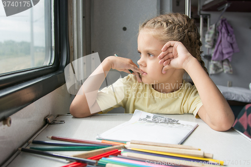 Image of The girl looked out the window thinking drawing pencils in a train