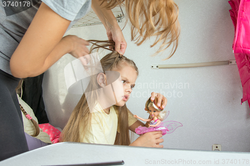 Image of Mom tries to unravel the tangled hair girl in a train