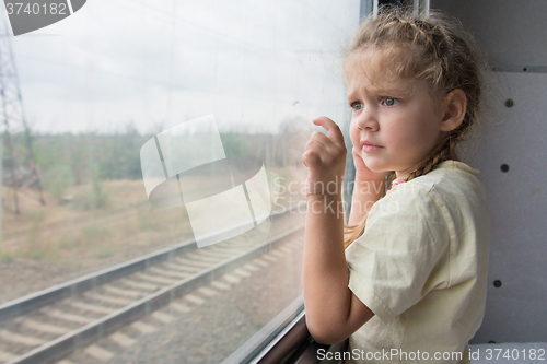 Image of Four-year girl with astonishment looks in the window of a train