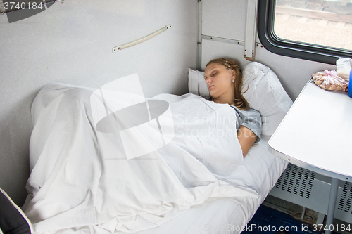 Image of Tired young girl sleeping on a train