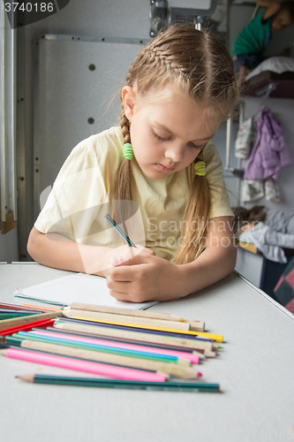 Image of Six year old girl with enthusiasm draws pencils in second-class train carriage