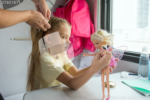 Image of  A girl playing with dolls until my mother weave braid of hair