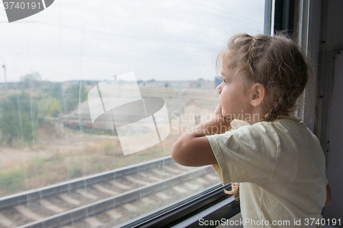 Image of The girl sadly looking out the window of a train car