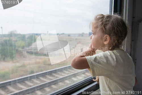 Image of The girl sadly looking out the window of a train car