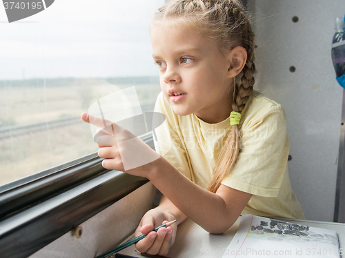 Image of Girl shows a finger in the second-class car of a train window