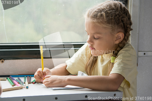 Image of Six year old girl draws pencils in second-class train carriage
