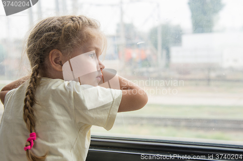 Image of Girl with anxiety and sadness looks out the window of the train car