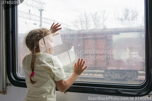 Image of The girl looks into the distance from the window of a train car