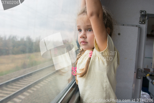 Image of  Four-year girl with astonishment looks in the window of a train