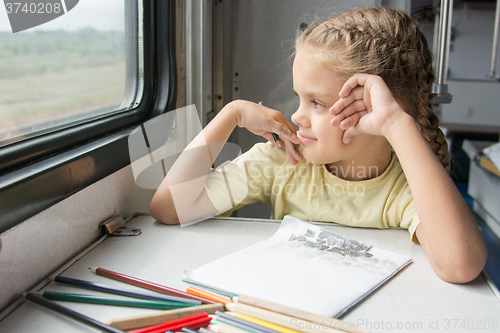 Image of The girl smiled happily looking out the window drawing pencils in a train