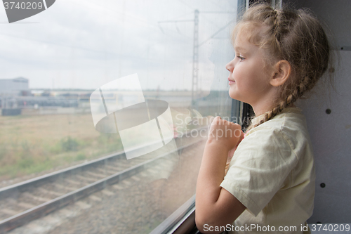 Image of Four-year girl looks out the window of the train car