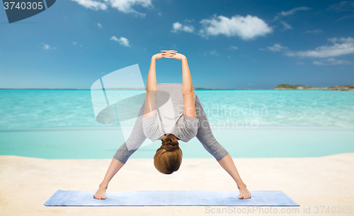 Image of woman making yoga  forward bend on beach 