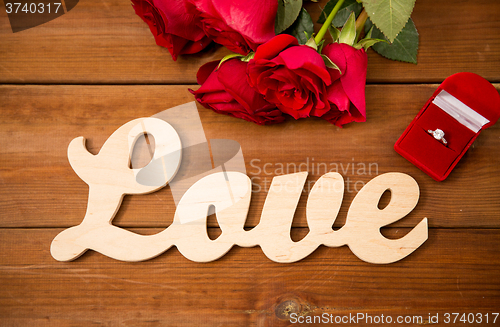 Image of close up of diamond ring, red roses and word love