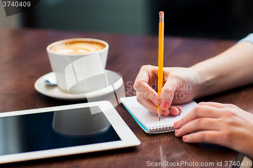 Image of close up of woman writing to notebook with pencil