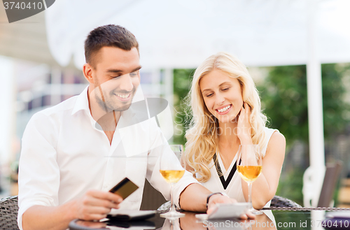 Image of happy couple with bank card and bill at restaurant