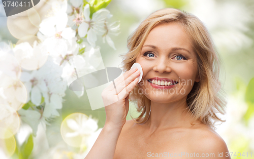 Image of happy woman cleaning face with cotton pad