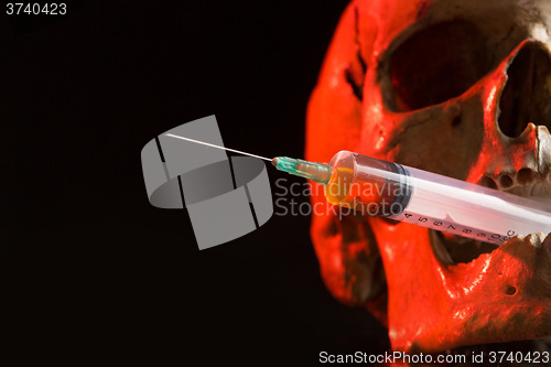 Image of Skull and syringe of yellowish liquid. concept drugs