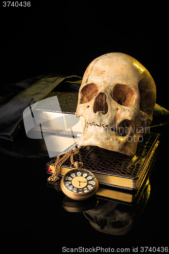 Image of human skull on a book next to the clock. concept of black magic