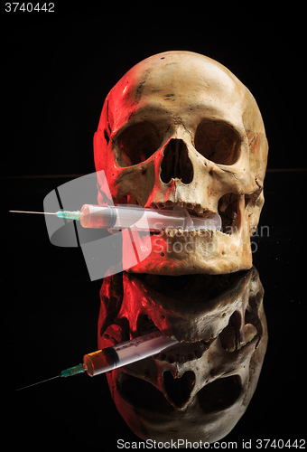 Image of Skull and syringe of yellowish liquid. concept drugs
