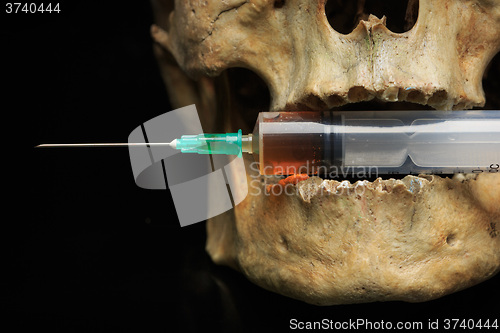 Image of Skull and syringe of yellowish liquid. concept drugs