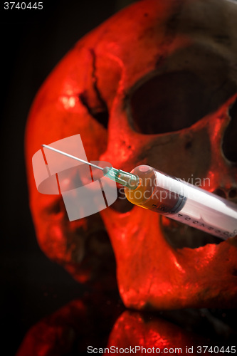 Image of Skull and syringe of yellowish liquid. concept drugs