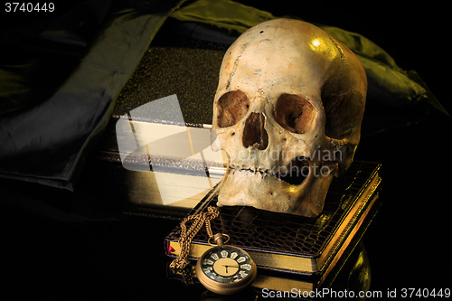Image of human skull on a book next to the clock. concept of black magic