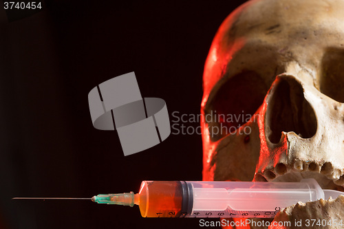 Image of Skull and syringe of yellowish liquid. concept drugs