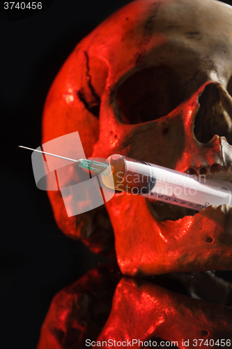 Image of Skull and syringe of yellowish liquid. concept drugs