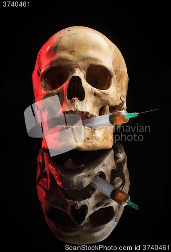 Image of Skull and syringe of yellowish liquid. concept drugs