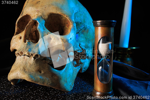 Image of human skull on a book next to the clock. concept of black magic