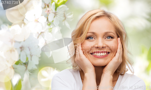 Image of smiling woman in white t-shirt touching her face