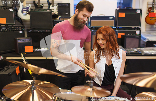 Image of man and woman with drum kit at music store