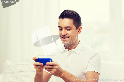 Image of happy man with smartphone at home