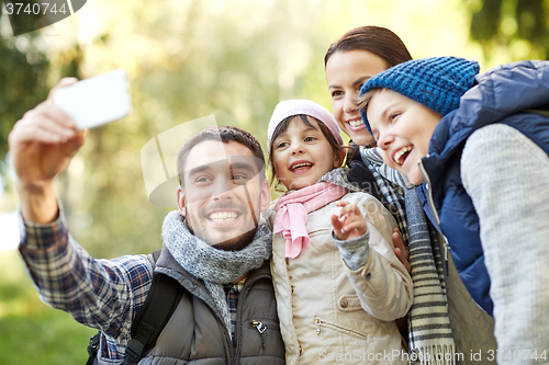 Image of family taking selfie with smartphone outdoors